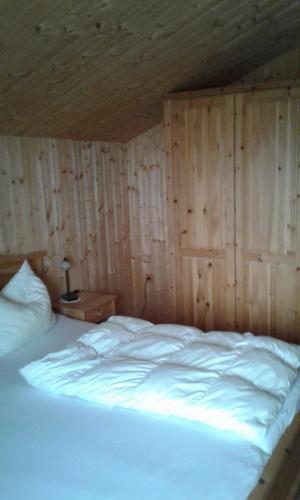 a bedroom with a white bed with a wooden wall at Leitenschneider Hütte in Waggendorf
