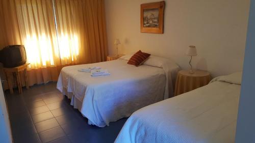Habitación de hotel con 2 camas y TV en Hosteria Tres Picos en Lago Puelo