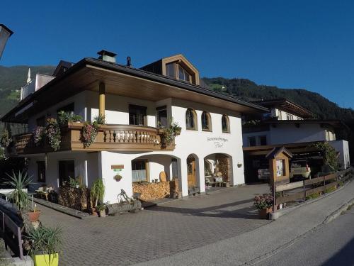 a large white building with a balcony on a street at Ferienwohnungen Flörl in Zell am Ziller
