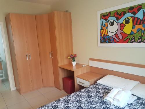 a bedroom with a bed and a desk and a painting at Apto de 02 qtos no Ingleses - Florianopolis - SC in Florianópolis