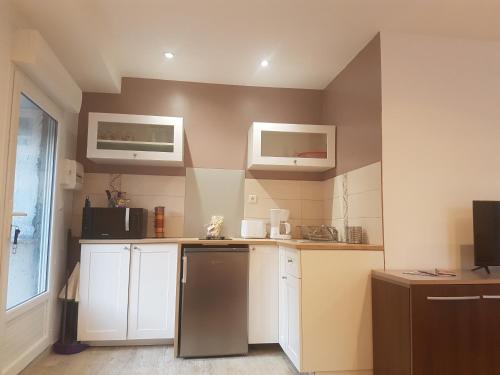 a small kitchen with white cabinets and a refrigerator at La petite bergerie in Roquebrune-sur-Argens