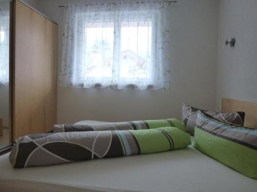 uma cama com almofadas verdes e cinzentas e uma janela em Ferienwohnung Hannes Steirer em Neustift im Stubaital