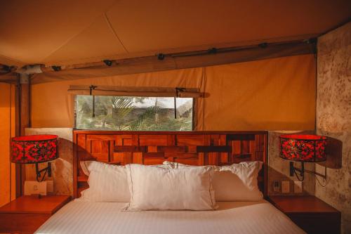 a bedroom with a bed with two lamps and a window at Serenity Authentic Glamping Tulum in Xpu Ha