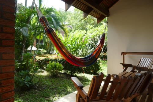 a hammock hanging from a porch with two chairs at Escape Caribeño in Puerto Viejo