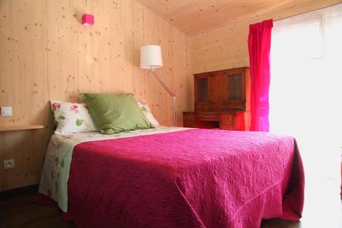 ein Schlafzimmer mit einem Bett mit einer rosa Decke und einem Fenster in der Unterkunft Maison Addama in Neyron