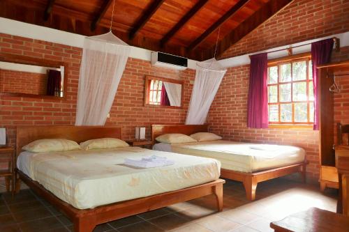 a bedroom with two beds and a brick wall at Escape Caribeño in Puerto Viejo