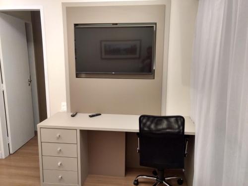 a desk with a television and a chair in a room at Tsue The Palace Flats in Sao Paulo