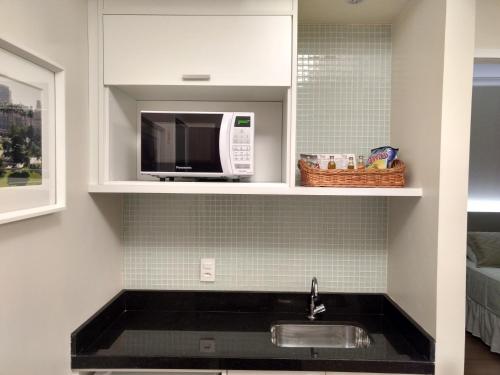 a kitchen with a sink and a microwave at Tsue The Palace Flats in Sao Paulo