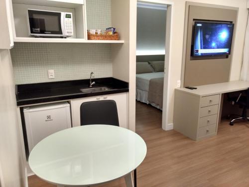 a small kitchen with a white table and a sink at Tsue The Palace Flats in Sao Paulo
