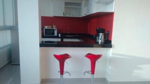a kitchen with red walls and a counter with red stools at Country Hotel in Chimbote