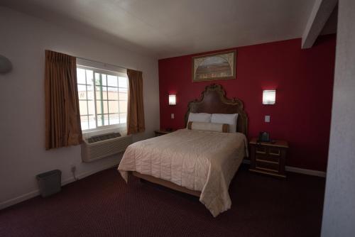 a red bedroom with a bed and a window at A Nights Inn in Ridgecrest