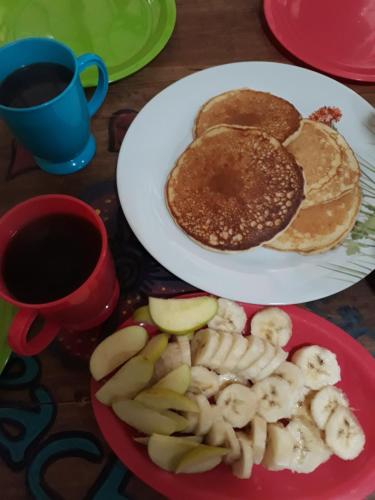 a plate of pancakes and apples and a cup of coffee at Casa Apapacho hostel in San Cristóbal de Las Casas