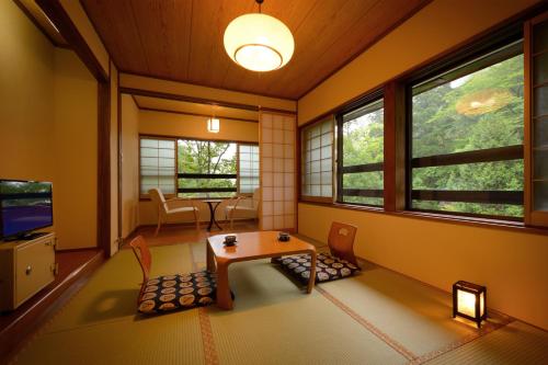 a living room with a table and chairs and windows at Namegawaonsen Fukushimaya in Yonezawa