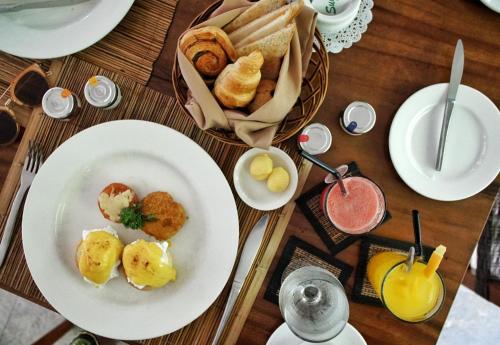 una mesa con platos de comida y una cesta de pan en Le Jardin Villas Seminyak, en Seminyak