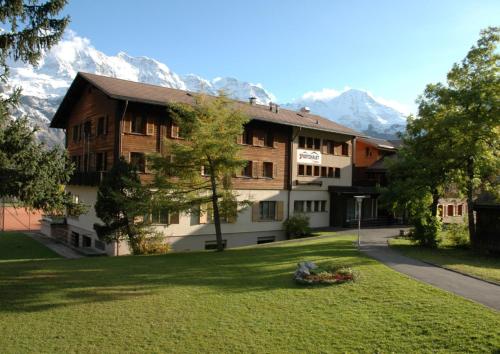 a large building with mountains in the background at Sportchalet Mürren in Mürren