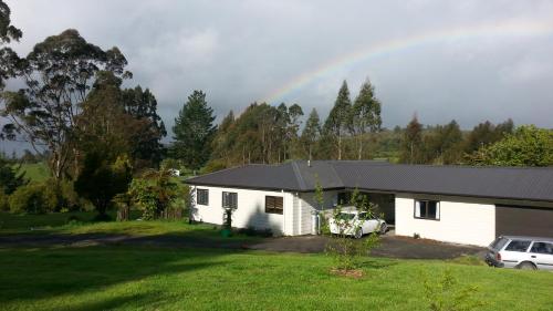 a house with a rainbow in the background at Rolling Hills Country Stay B&B in Tauranga