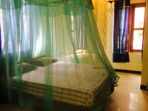a bed with a canopy in a room with curtains at Beach Hut in Arugam Bay