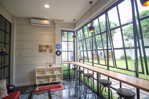 a bar with stools in a room with large windows at Rumah Kertajaya in Surabaya