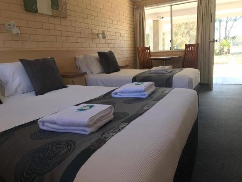 a hotel room with three beds with towels on them at The Edgewater at Burrill in Ulladulla