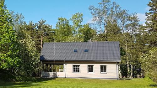 a white house with a gray roof in a field at Sea House Dzelmes in Mazirbe