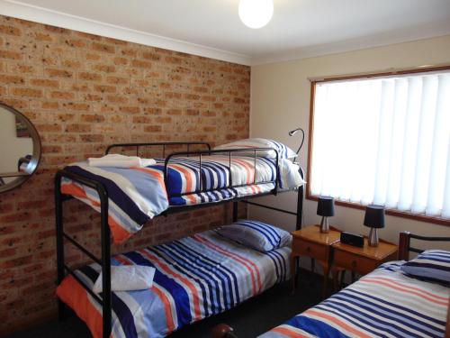 - une chambre avec 2 lits superposés et un mur en briques dans l'établissement Dalmeny Shores Villas, à Dalmeny