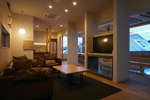 a living room with a couch and a tv and a table at Fuyunoki in Furano