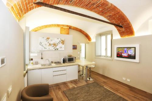 アルバにあるAppartamento San Giuseppeの白いキャビネットとレンガの天井が備わるキッチン