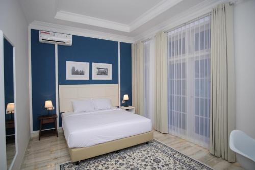 a bedroom with a white bed and blue walls at Rumah Kertajaya in Surabaya