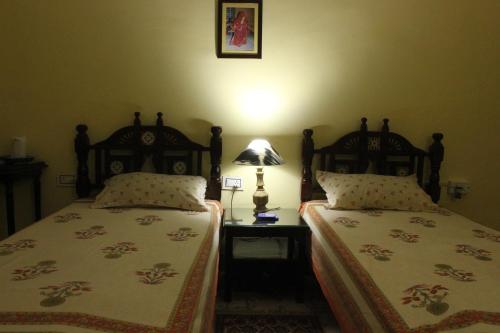 a bedroom with two beds and a lamp on a table at Udai Niwas - a boutique homestay in Bikaner