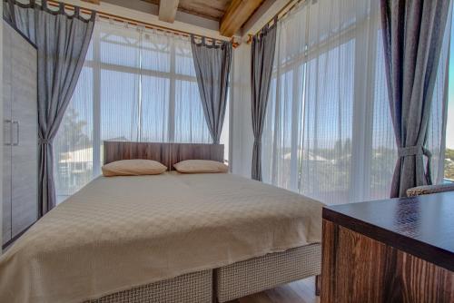 a bedroom with a bed and large windows at Hillside Karakol B&B in Karakol