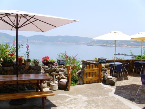 un patio con mesas y sombrillas con vistas al agua en Furen Homestay, en Nangan