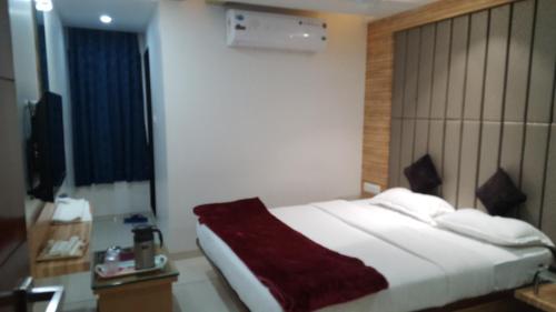 a hotel room with a bed and a television at Hotel The Furat Inn in Vapi
