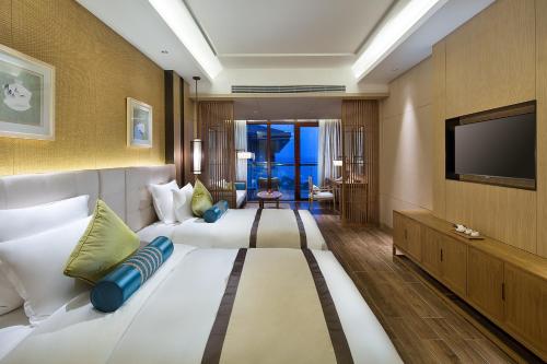 a hotel room with a large bed and a flat screen tv at Wyndham Grand Plaza Royale Wenchang in Wenchang