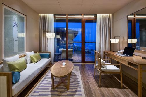 a living room with a couch and a desk with a laptop at Wyndham Grand Plaza Royale Wenchang in Wenchang