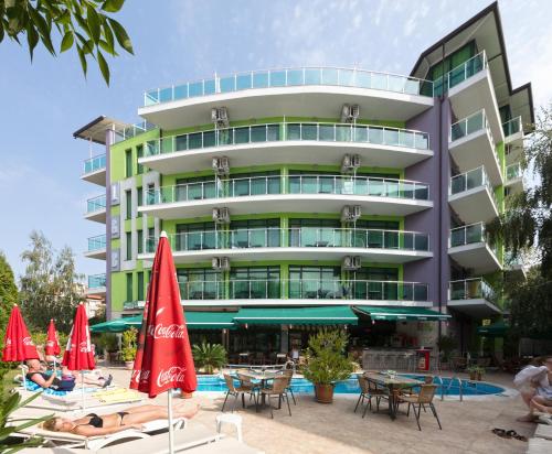 a hotel with chairs and umbrellas in front of a building at Hotel L&B- Free parking in Sunny Beach