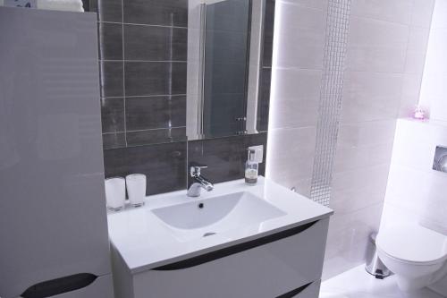 a white bathroom with a sink and a toilet at Apartament Wilga Park in Krakow