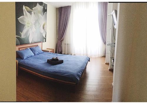 a bedroom with a bed with a blue blanket and a window at Apartment on Lukyanovska in Kyiv