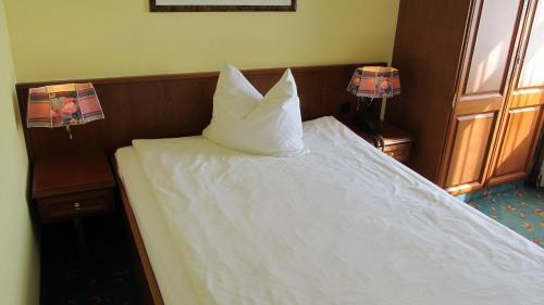 a bed with a white pillow on top of it at Brandiser Parkhotel in Brandis