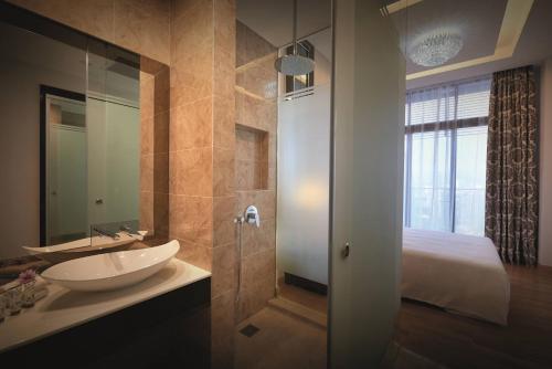 a bathroom with a sink and a shower and a bed at Dorsett Kuala Lumpur in Kuala Lumpur