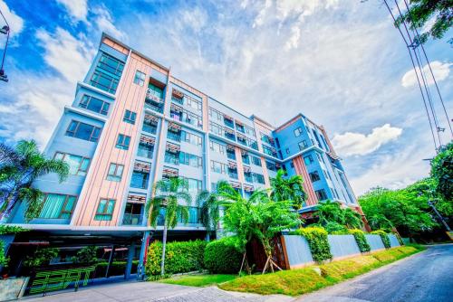 a tall building with palm trees in front of a street at Tree Boutique Residence - Quiet Oasis - Stunning View, Pool & Gym in Chiang Mai