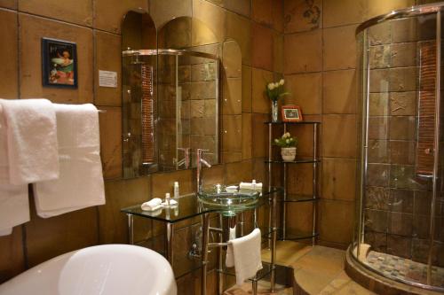 a bathroom with a glass shower and a sink at Le Chateau Guest House and Conference Centre in Kempton Park