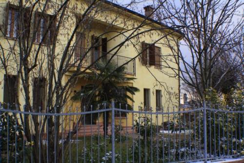 a yellow house with a fence in front of it at B&B Nascondino in Goito