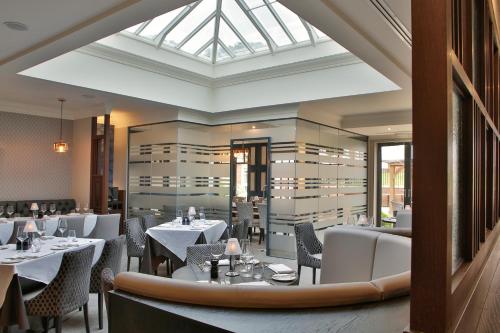a restaurant with white tables and chairs and a skylight at Manor Hotel Solihull, BW Signature Collection in Bickenhill