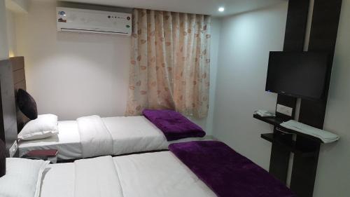 a hotel room with two beds and a flat screen tv at Hotel The Furat Inn in Vapi