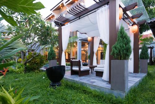a patio with a white pergola with chairs and plants at Dai An Phu Villa in Hoi An