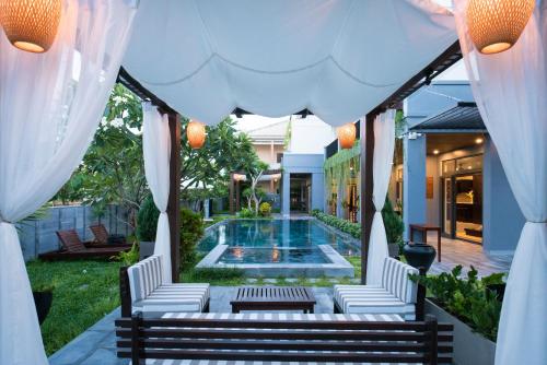 a patio with white chairs and a swimming pool at Dai An Phu Villa in Hoi An