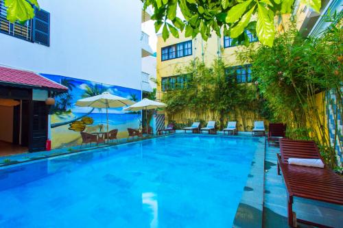 a large swimming pool with chairs and umbrellas next to a building at Hoi An Hai Au Boutique Hotel in Hoi An