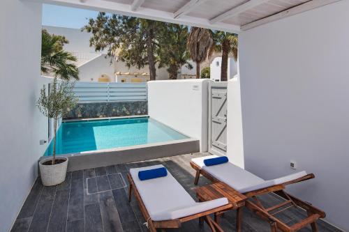 a patio with two chairs and a swimming pool at Meltemi Excelsior Suites in Perissa