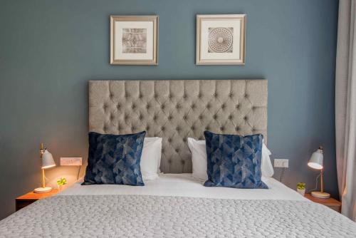 a bedroom with a large bed with blue walls at M-Hotels Apartments in London
