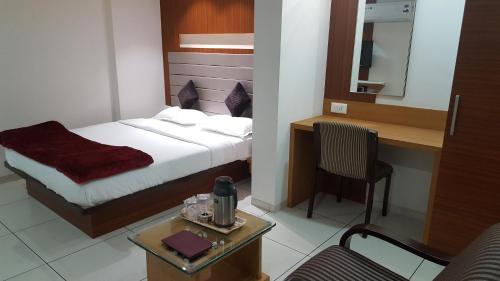 a bedroom with a bed and a table with a chair at Hotel The Furat Inn in Vapi
